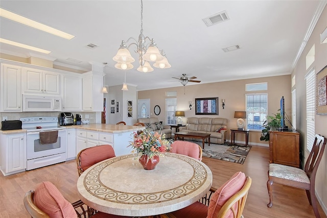 dining room with visible vents, light wood-style flooring, ceiling fan with notable chandelier, and ornamental molding