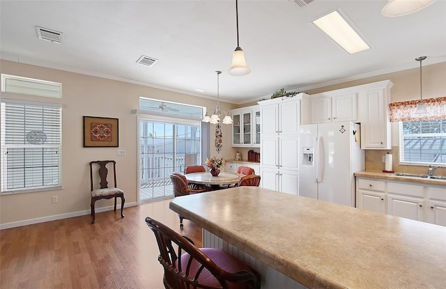 kitchen with visible vents, a kitchen bar, ornamental molding, a sink, and white fridge with ice dispenser