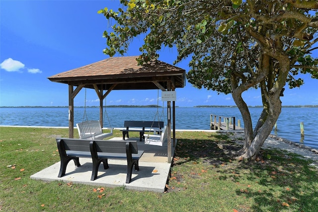 surrounding community featuring a lawn, a water view, and a boat dock