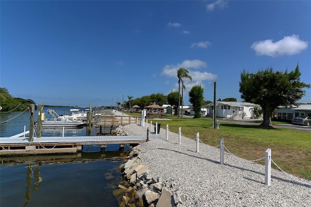 view of dock with a yard and a water view