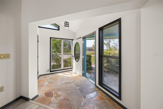 entrance foyer with stone finish flooring, baseboards, and vaulted ceiling