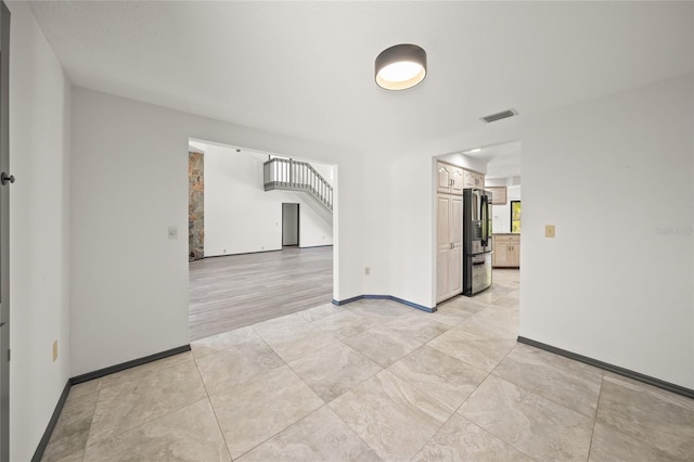 unfurnished room featuring light tile patterned floors, visible vents, stairway, and baseboards