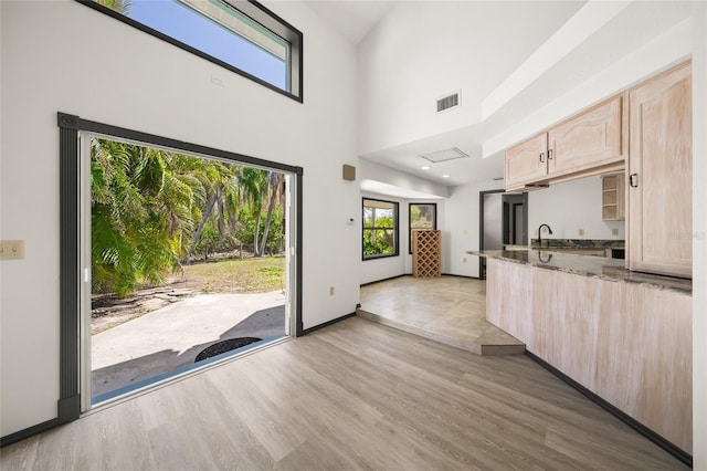 kitchen with dark stone countertops, visible vents, light wood-style floors, and light brown cabinetry