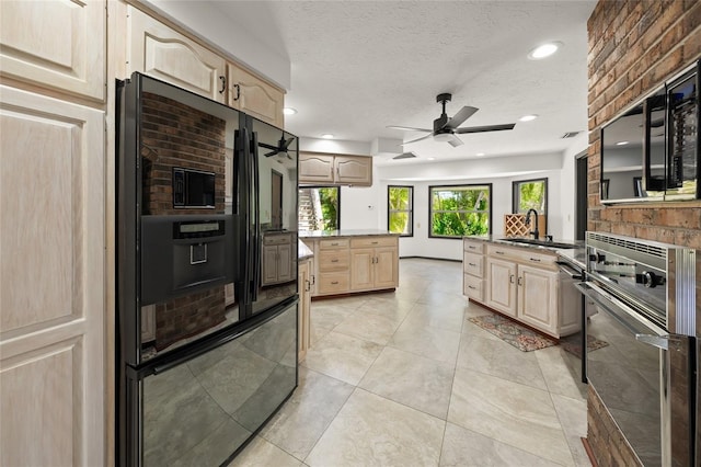 kitchen with light brown cabinets, a textured ceiling, black appliances, a ceiling fan, and a sink