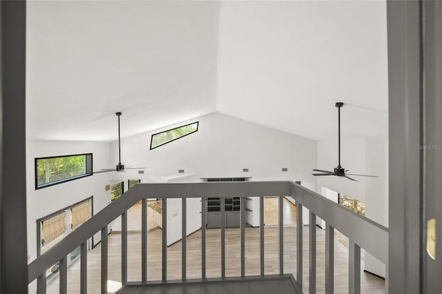 stairway with a ceiling fan, vaulted ceiling, and wood finished floors