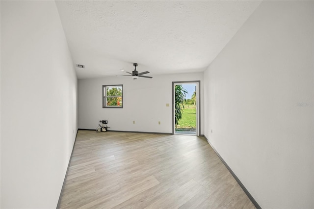 unfurnished room with a ceiling fan, baseboards, visible vents, light wood-style floors, and a textured ceiling