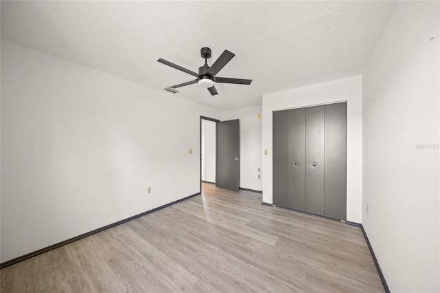 unfurnished bedroom featuring a closet, light wood-style flooring, baseboards, and ceiling fan