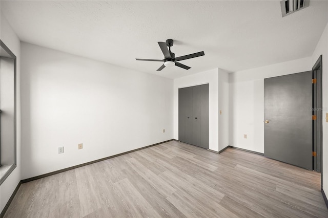 unfurnished bedroom with visible vents, baseboards, light wood-style flooring, and a ceiling fan