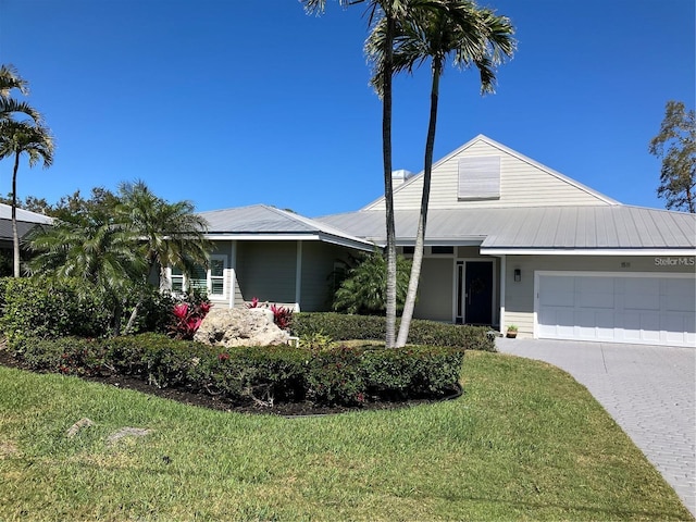 view of front facade with a front lawn, an attached garage, driveway, and metal roof