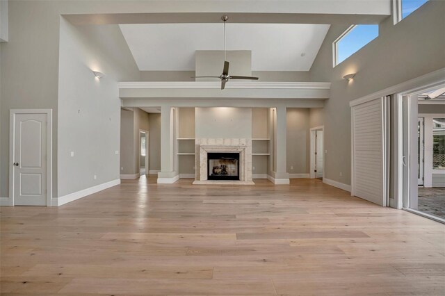 unfurnished living room with baseboards, high vaulted ceiling, light wood-style floors, and a ceiling fan