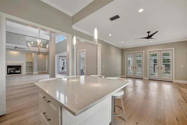 kitchen with visible vents, white cabinetry, light wood-type flooring, ceiling fan with notable chandelier, and open floor plan