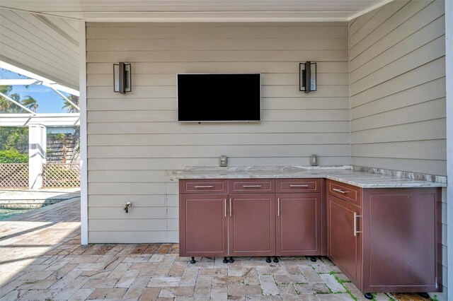 view of patio featuring glass enclosure and exterior kitchen