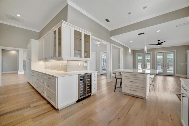 kitchen featuring wine cooler, french doors, a breakfast bar, light wood-type flooring, and white cabinets