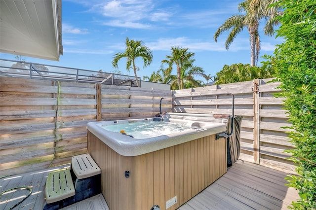wooden terrace featuring a hot tub and fence