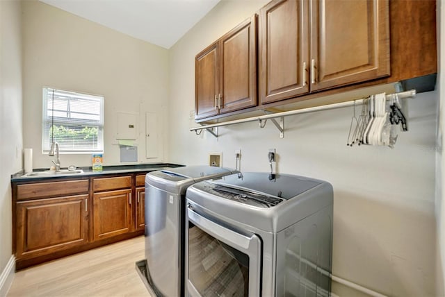 laundry room featuring separate washer and dryer, light wood-style floors, cabinet space, and a sink