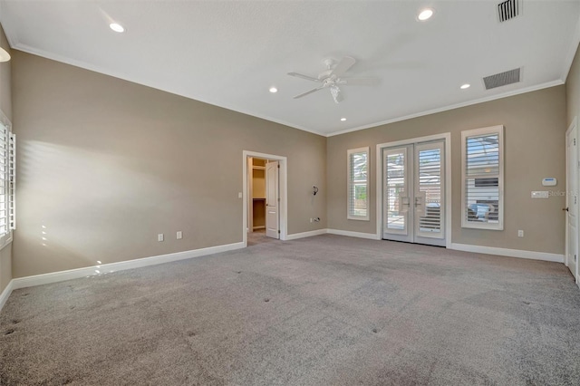 carpeted spare room with baseboards, visible vents, crown molding, and ceiling fan