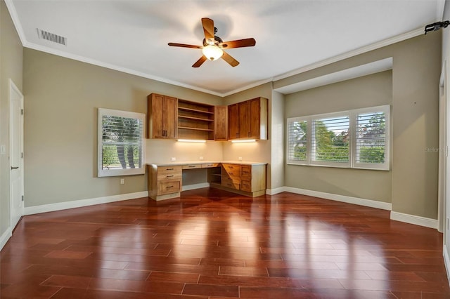 unfurnished office featuring built in desk, dark wood finished floors, a wealth of natural light, visible vents, and ceiling fan
