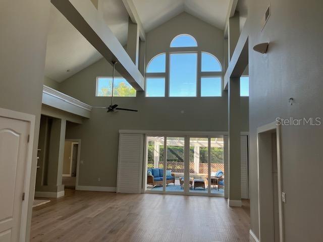 unfurnished living room with plenty of natural light, baseboards, visible vents, and wood finished floors