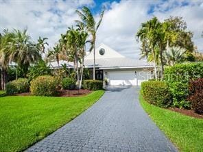 single story home with driveway, an attached garage, and a front lawn