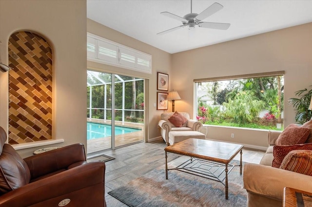 living room featuring baseboards, plenty of natural light, and ceiling fan