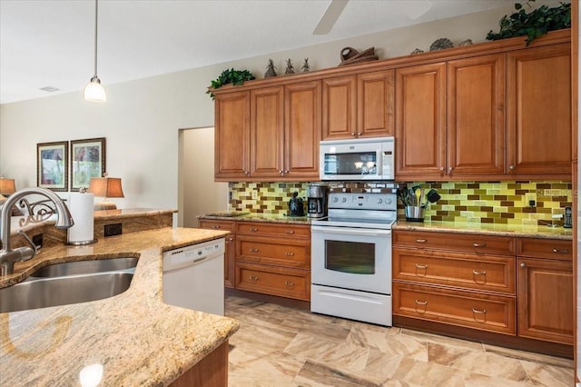 kitchen with brown cabinets, a sink, white appliances, light stone countertops, and hanging light fixtures