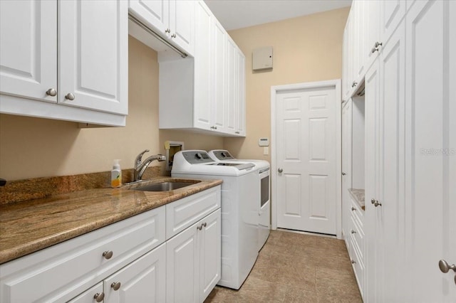 washroom with cabinet space, washing machine and dryer, and a sink