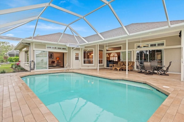 outdoor pool featuring glass enclosure, a patio, a ceiling fan, and an outdoor hangout area