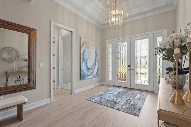 foyer entrance featuring a raised ceiling, crown molding, and french doors