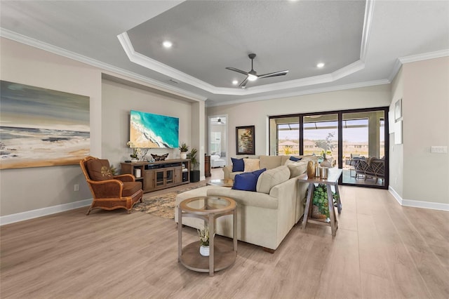 living area with a ceiling fan, baseboards, crown molding, light wood-style floors, and a raised ceiling