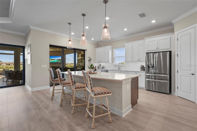 kitchen featuring a breakfast bar area, visible vents, a kitchen island, a sink, and stainless steel fridge