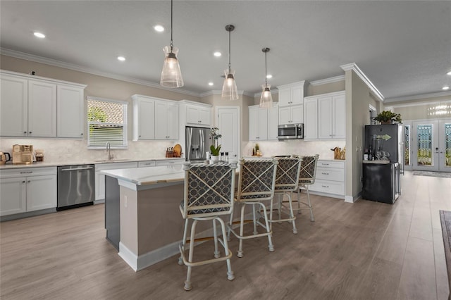 kitchen with a sink, stainless steel appliances, a breakfast bar, and light wood finished floors