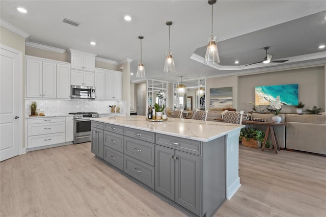 kitchen with white cabinets, gray cabinetry, open floor plan, and stainless steel appliances