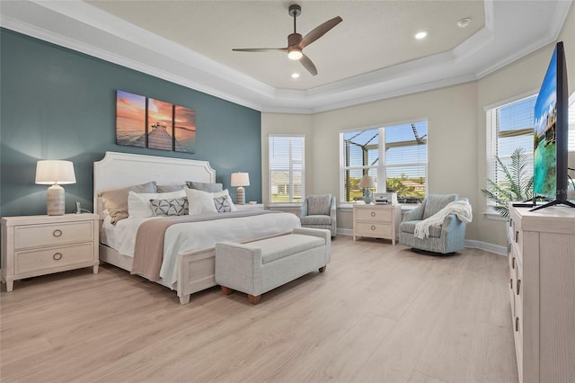 bedroom featuring ceiling fan, baseboards, a tray ceiling, ornamental molding, and light wood-style flooring