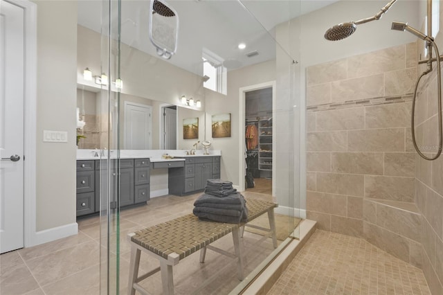 full bath with tile patterned floors, a walk in closet, vanity, and a tile shower