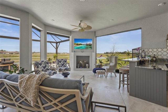 living area featuring a textured ceiling, a ceiling fan, and a textured wall