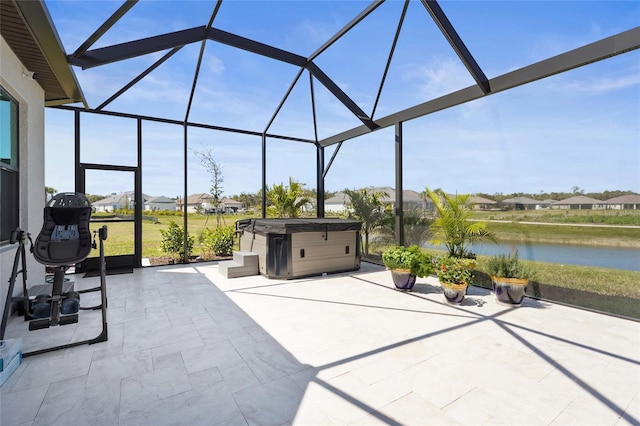 view of patio featuring a lanai, a water view, and a hot tub