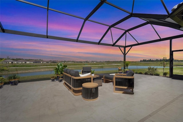 patio terrace at dusk with glass enclosure, a water view, and an outdoor hangout area