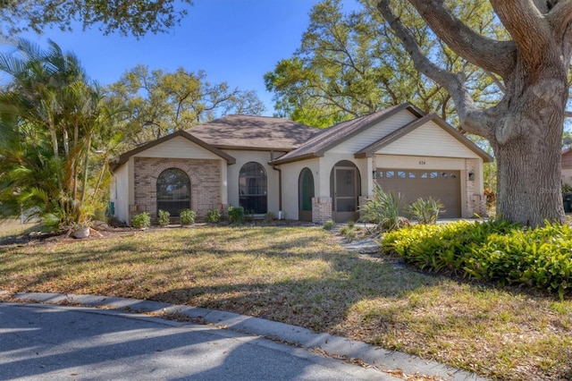 view of front of house with brick siding, stucco siding, an attached garage, and a front lawn