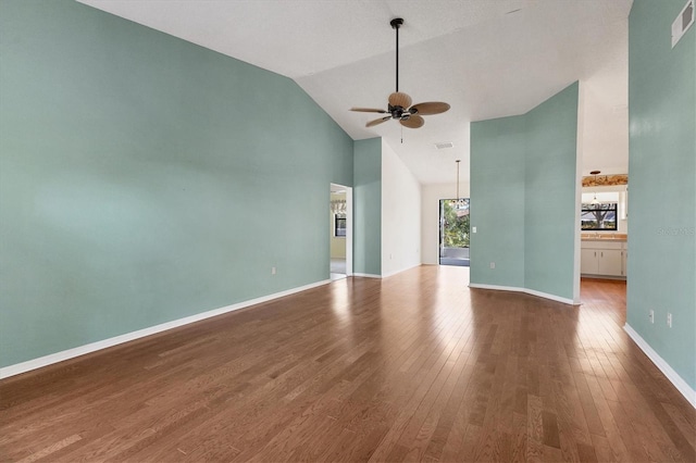 unfurnished living room with wood finished floors, visible vents, baseboards, high vaulted ceiling, and ceiling fan with notable chandelier