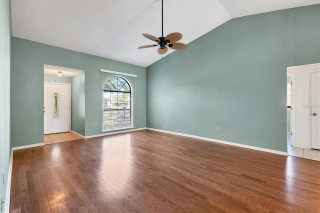 unfurnished living room with ceiling fan, high vaulted ceiling, baseboards, and wood finished floors