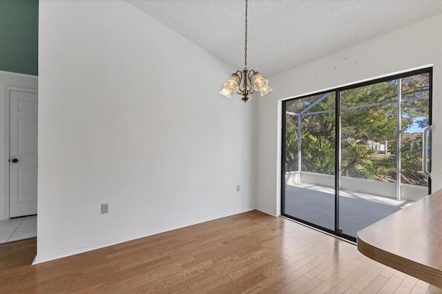 interior space featuring baseboards, a chandelier, lofted ceiling, wood finished floors, and a textured ceiling