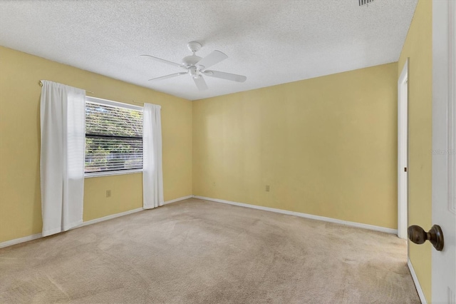 carpeted spare room featuring baseboards, a textured ceiling, and a ceiling fan