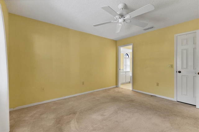 spare room with visible vents, light carpet, a textured ceiling, and baseboards