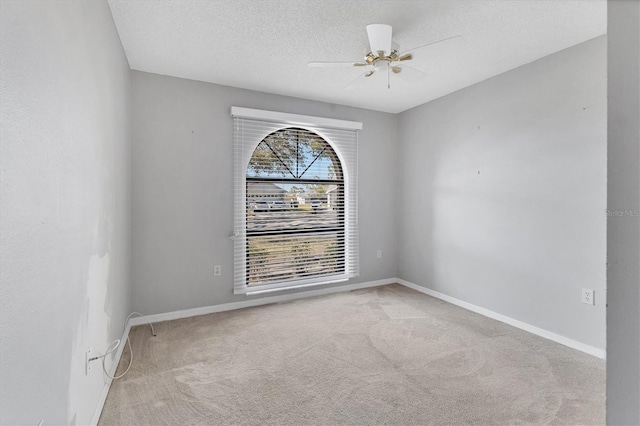 carpeted spare room with a ceiling fan, baseboards, and a textured ceiling