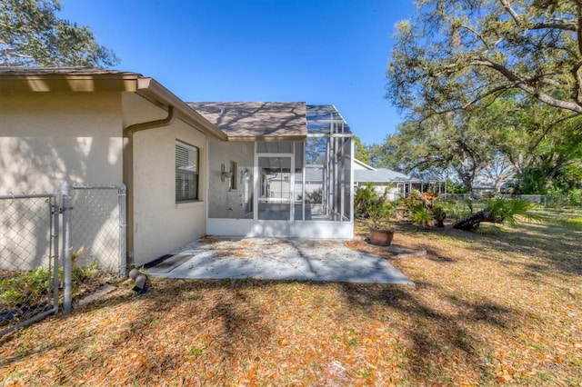 back of property with stucco siding, a lawn, a gate, a patio, and fence