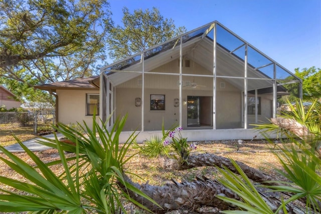 rear view of property with a lanai, ceiling fan, and fence