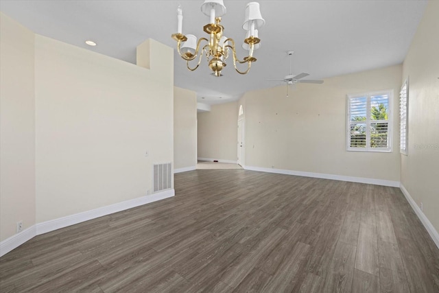 spare room with ceiling fan with notable chandelier, visible vents, wood finished floors, and baseboards