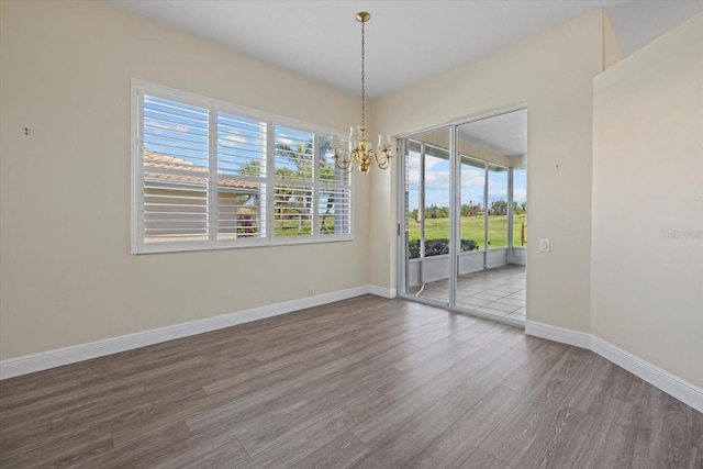 unfurnished dining area with baseboards, an inviting chandelier, and wood finished floors