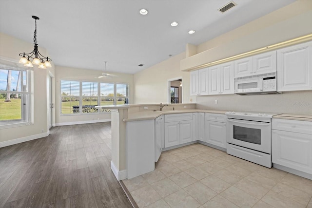 kitchen featuring visible vents, light countertops, a peninsula, white appliances, and a sink