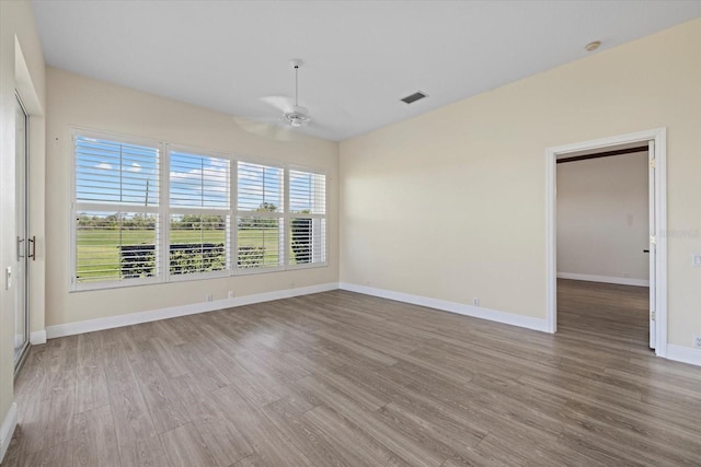 spare room featuring ceiling fan, visible vents, baseboards, and wood finished floors